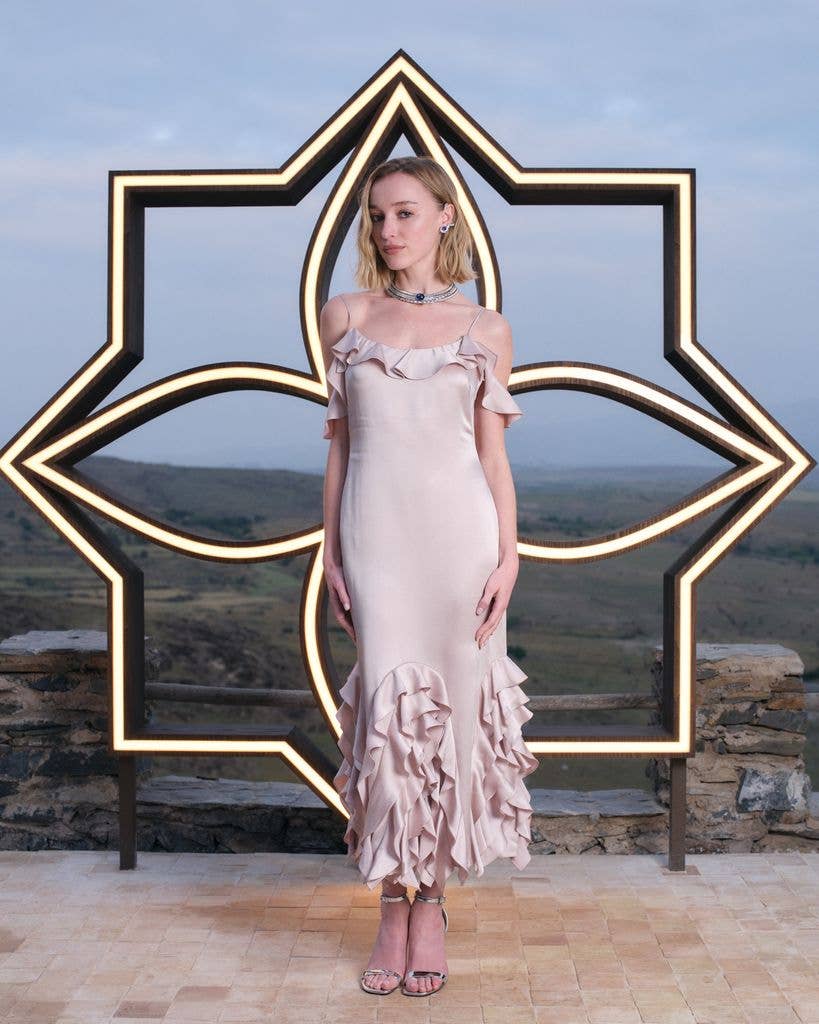 Phoebe Dynevor wears a pale pink silk dress with silver sandals.
Phoebe Dynevor also wears wears Gravité necklace set with a 27.20-carats cabochon-cut sapphire, from the Louis Vuitton High Jewelry Awakened Hands, Awakened Minds Collection, Motion earcuffs set with two oval step-cut sapphires of 4.55 carats and 4.64 carats, and Gravité ring set with a 2.49-carats oval-cut sapphire, from the Louis Vuitton High Jewelry Awakened Hands, Awakened Minds Collection. 
